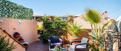 A patio with wicker furniture, potted plants, and a clear blue sky.