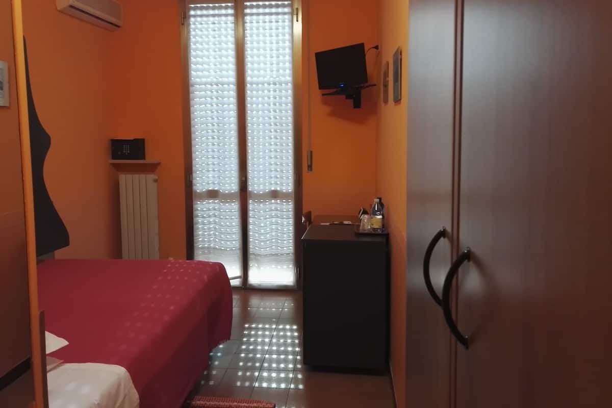A room with a bed, a desk, a TV, and a wardrobe.