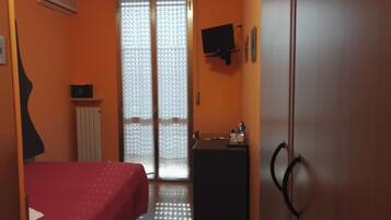 Una habitación con cama, escritorio, televisor y armario.