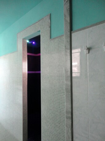A bathroom with a tiled wall and a door.