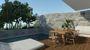 A poolside area with a stone wall, a wooden table with chairs, and a white bench. - Rainbow Apartments (Hersonissos)