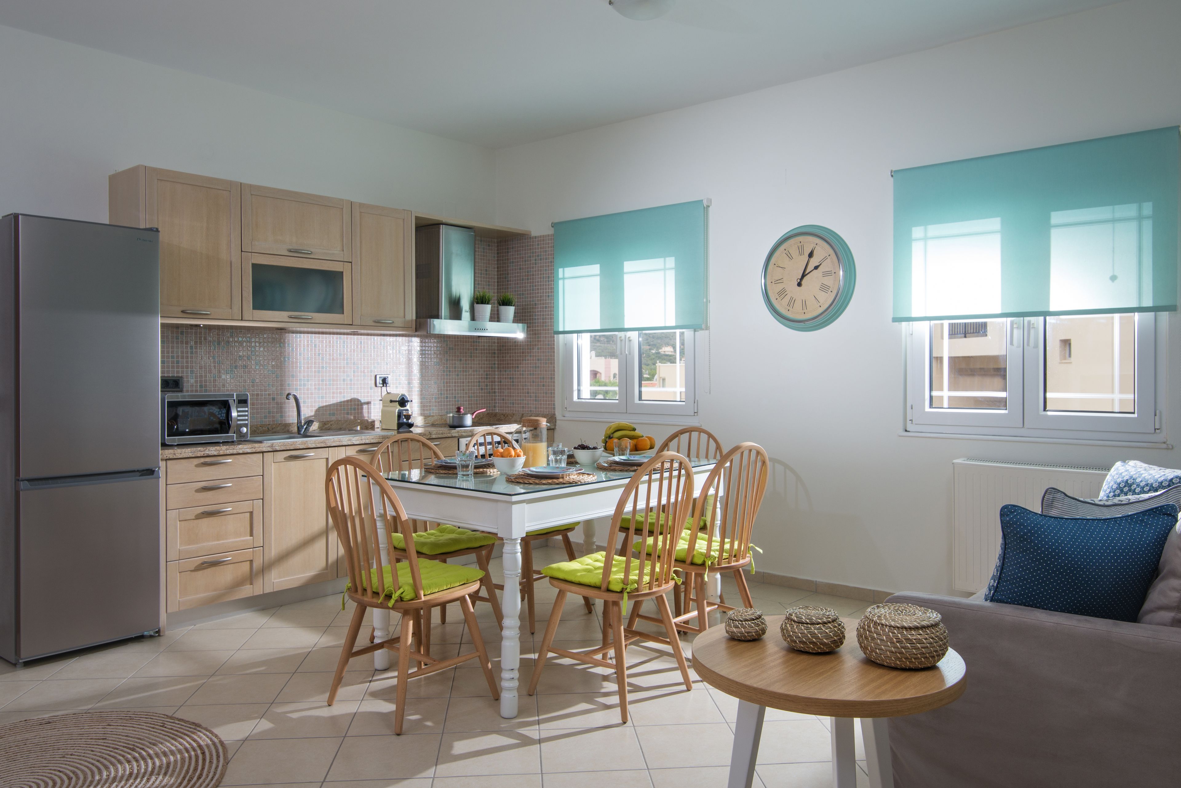 A modern kitchen with wooden cabinets, a refrigerator, a microwave, and a dining table with chairs.