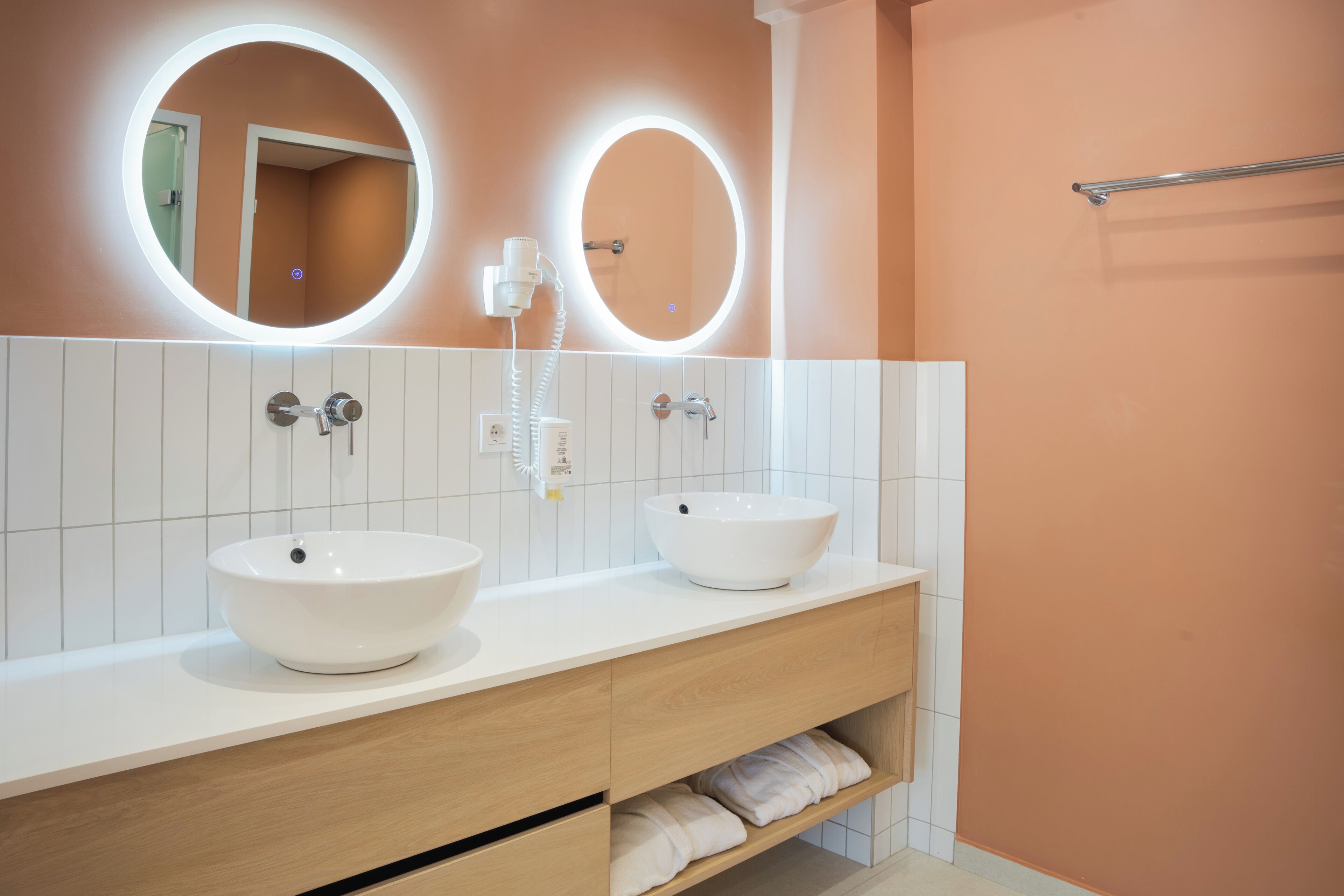 Ein Badezimmer mit zwei Waschbecken, einem Spiegel und einem Handtuchhalter.