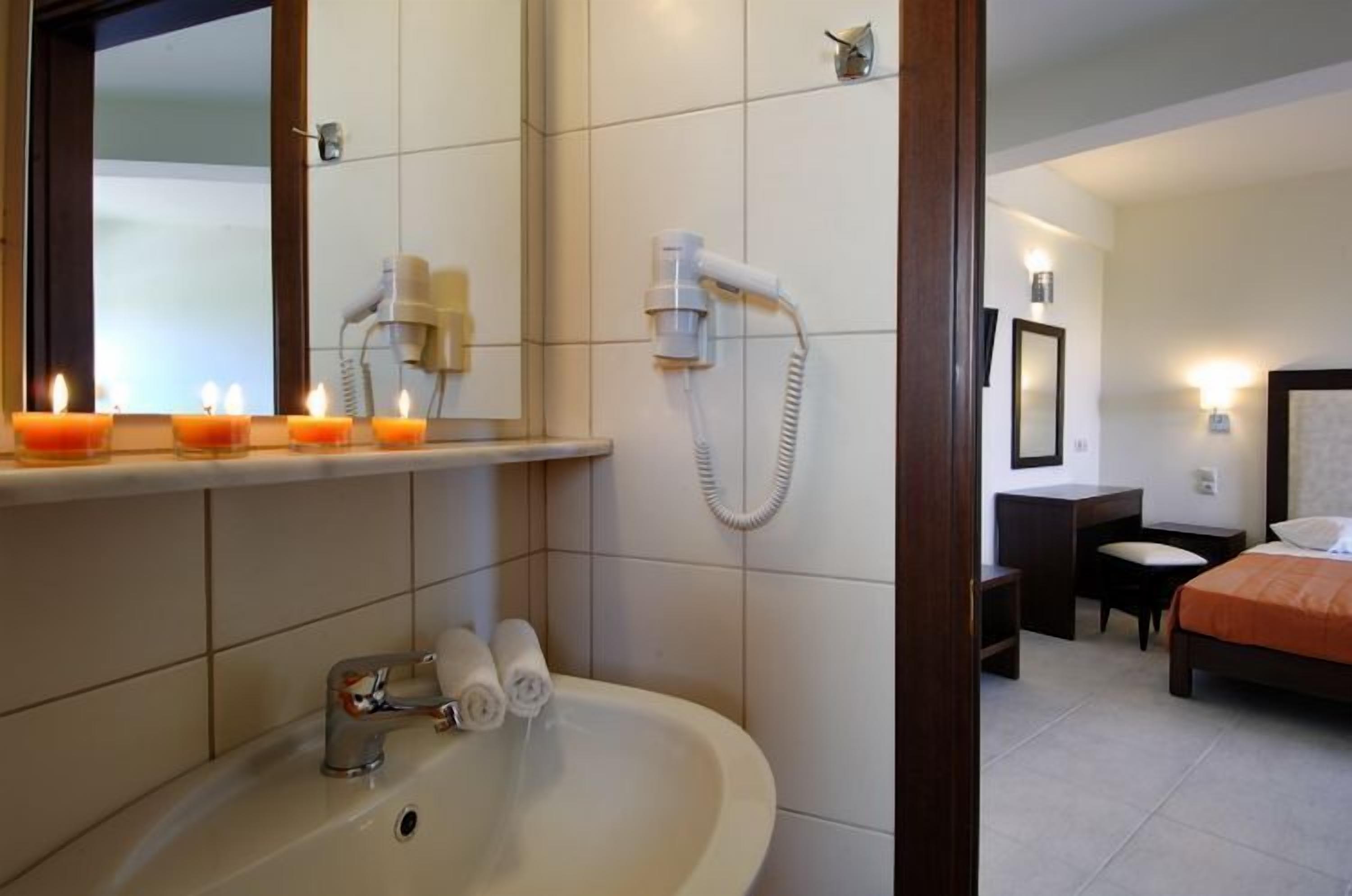 Ein Hotelbad mit Waschbecken, Spiegel, Haartrockner und Dusche.