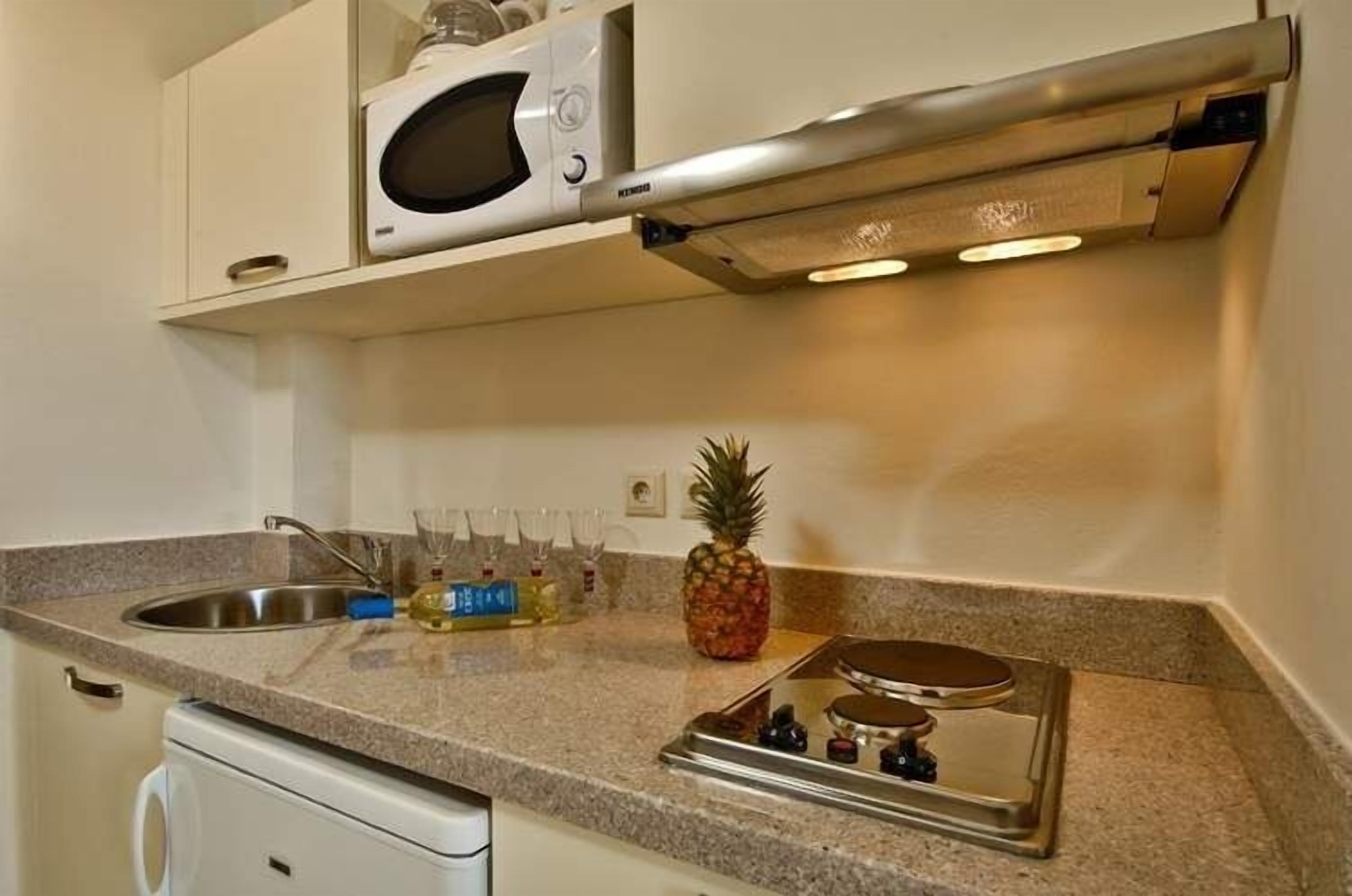 Une cuisine équipée d’un four à micro-ondes, d’un évier en acier inoxydable et d’une cuisinière.