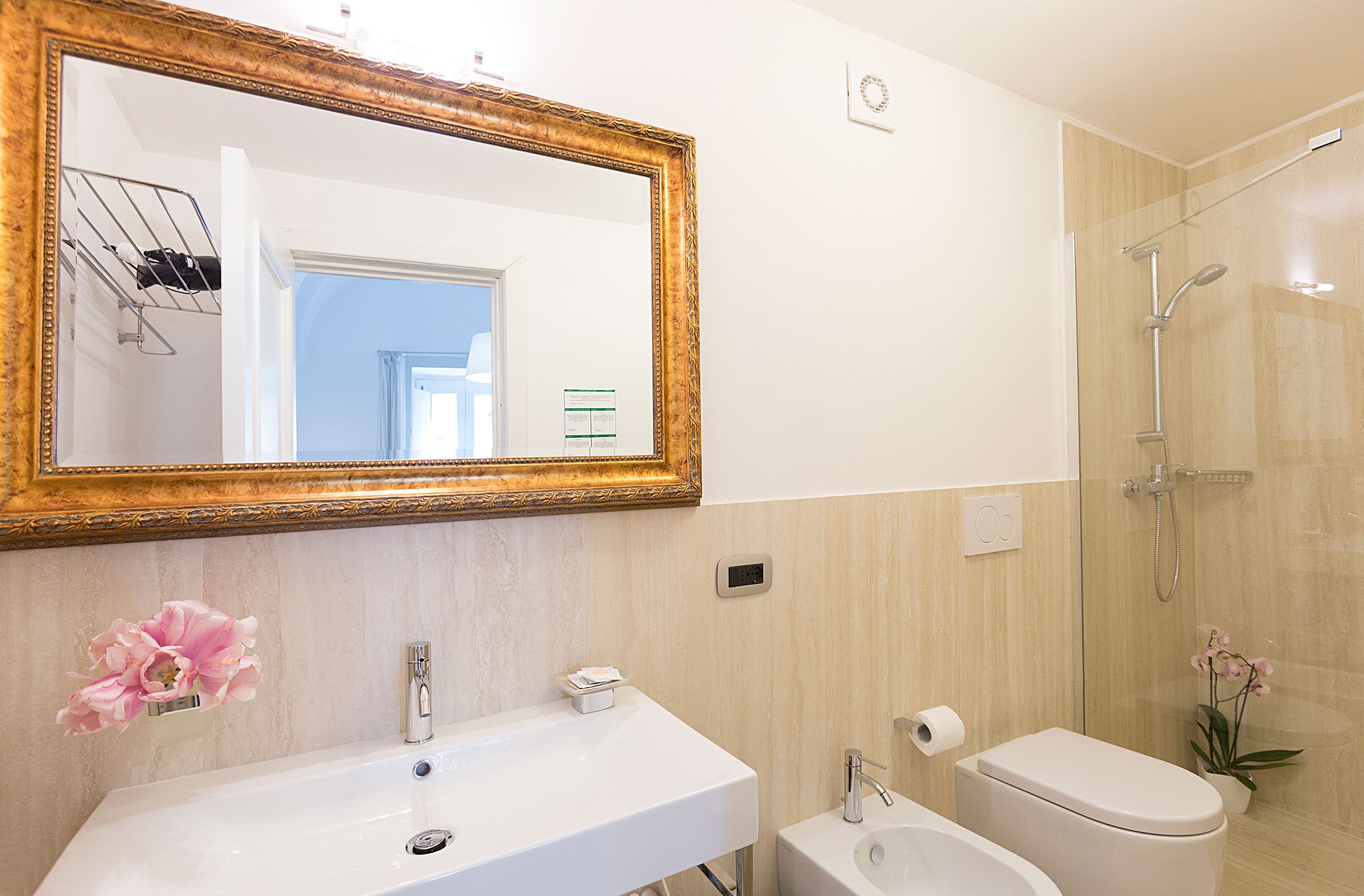 Ein Badezimmer mit großem Spiegel, Waschbecken, Toilette und Dusche.