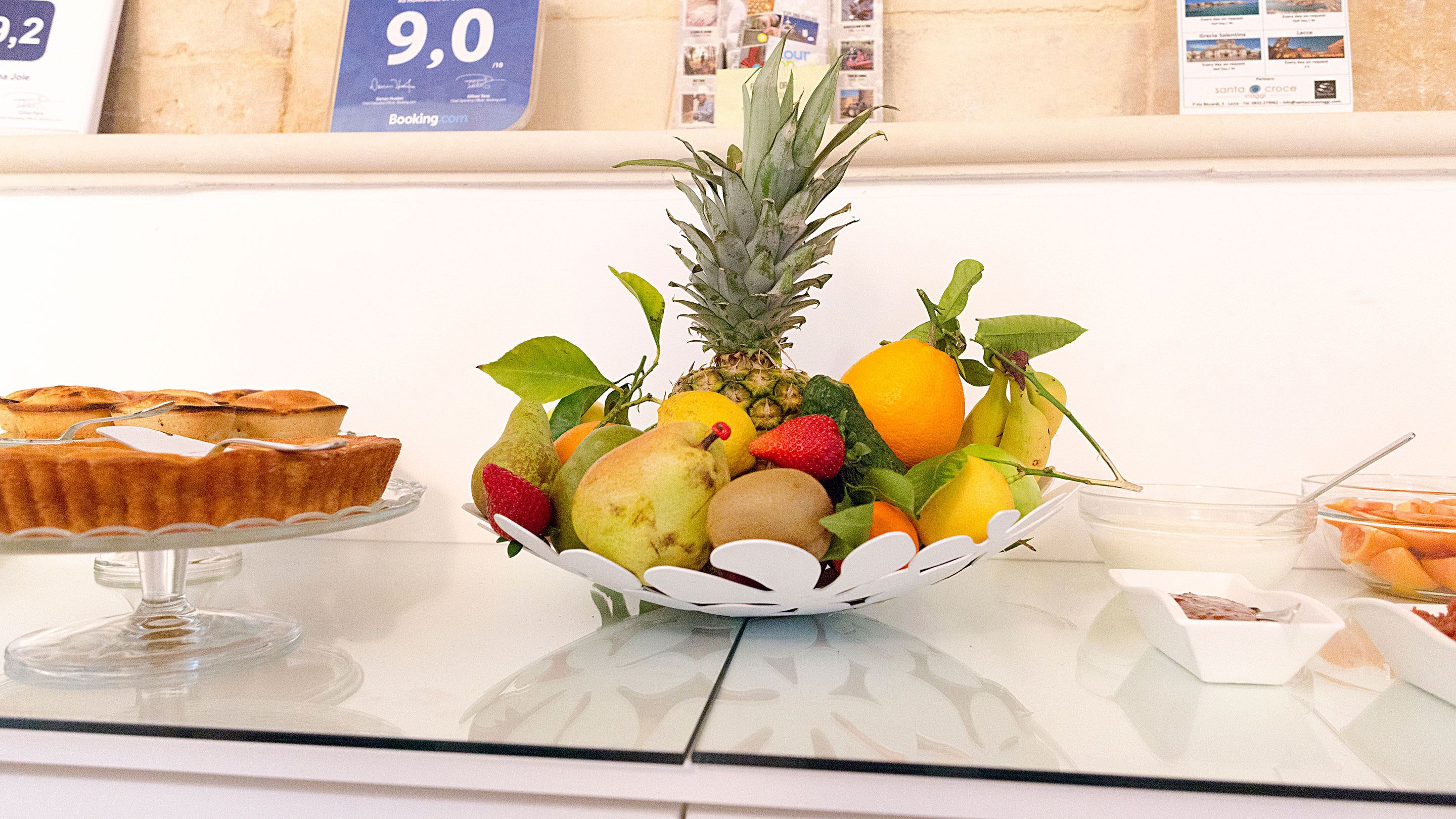 Eine Obstschale auf einem Tisch mit Ananas, Erdbeeren, Orangen und Birnen.