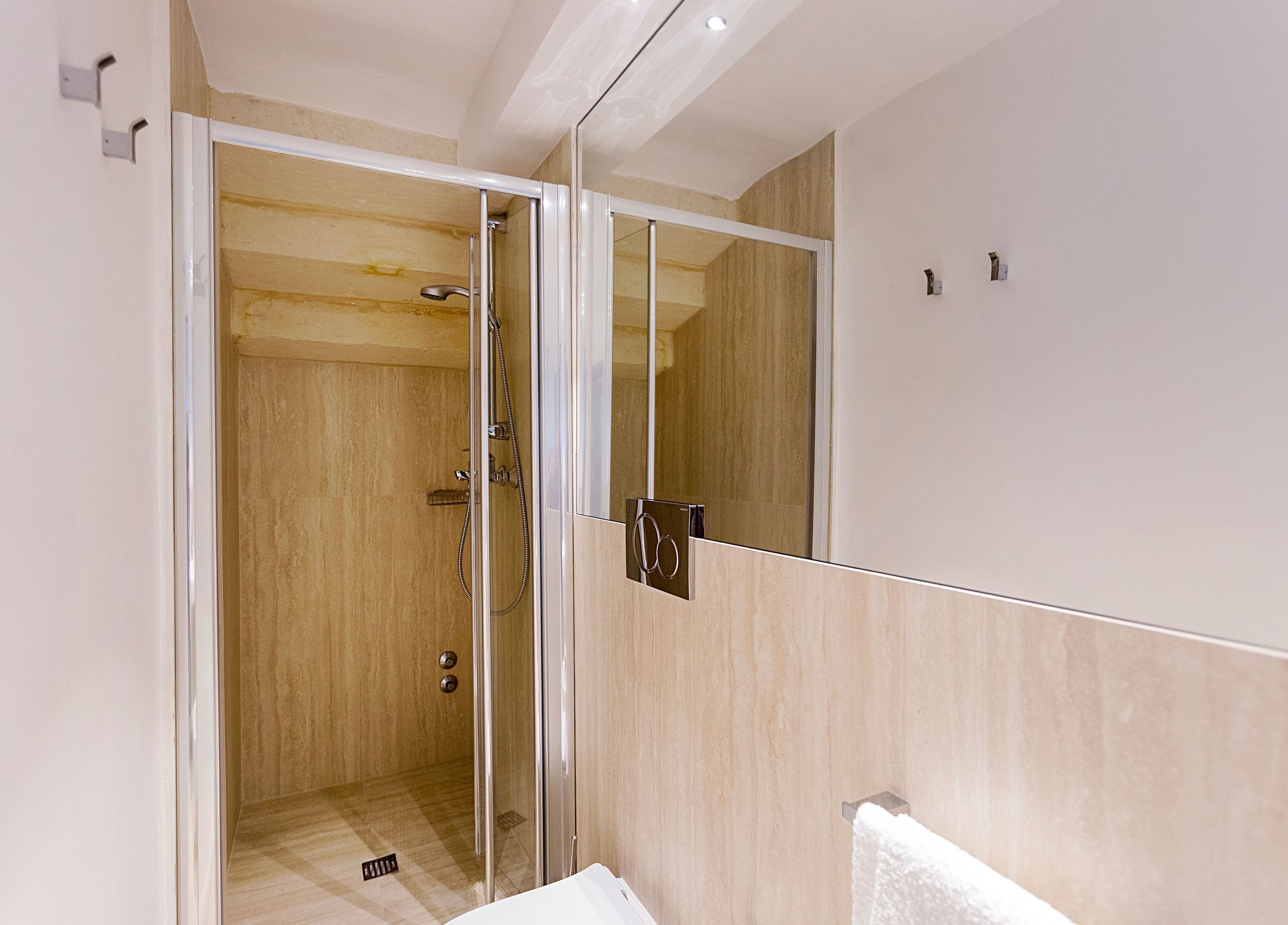 A modern bathroom with a glass-enclosed shower, a mirror, and a towel rack.