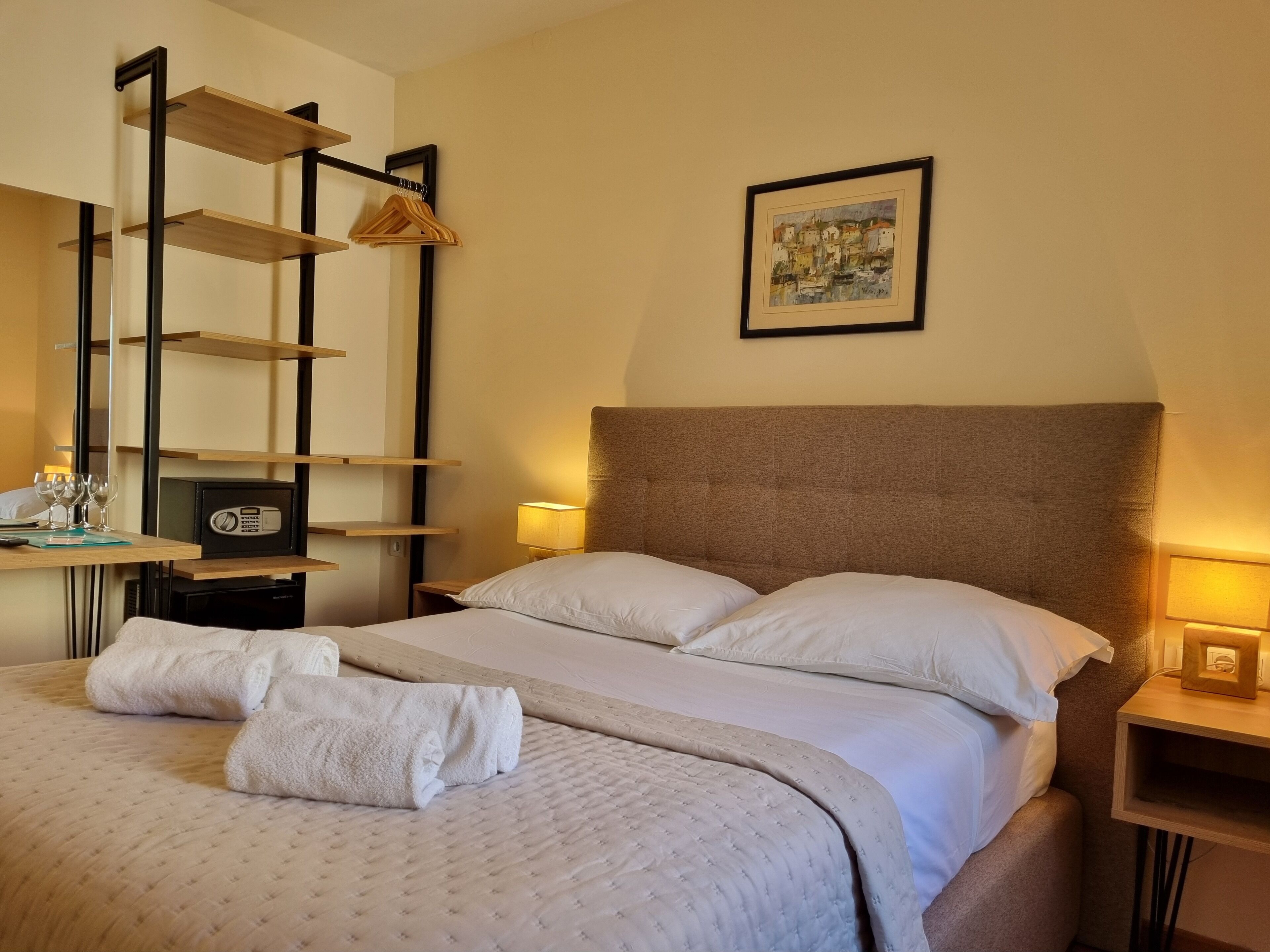 A neatly made bed with white linens, a headboard, and a bedside table with a lamp.
