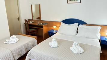 Habitación de hotel con dos camas, un escritorio, una silla, un espejo y una mesita de noche con lámpara.