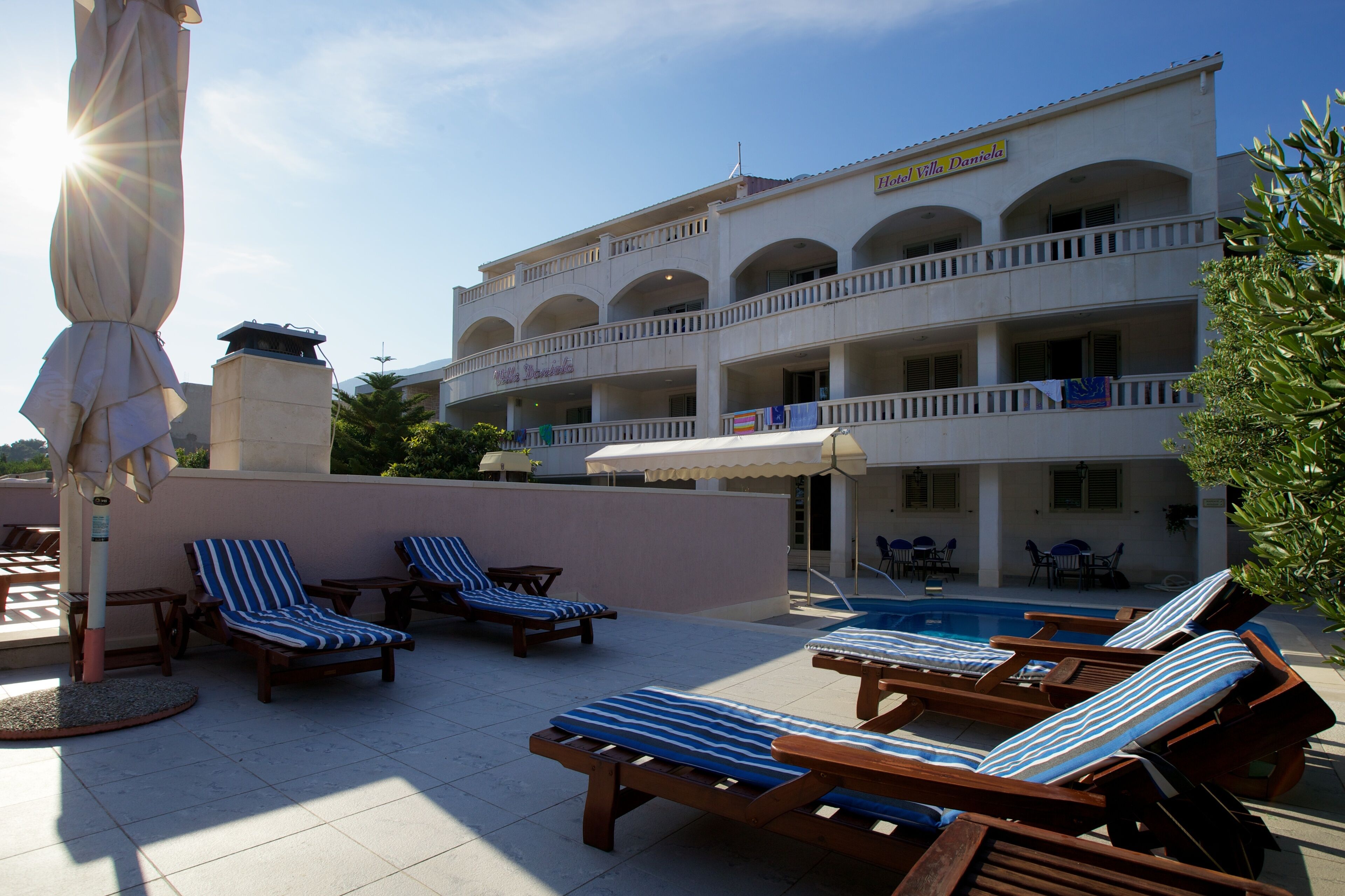 A hotel with multiple balconies, a swimming pool, and sun loungers.
