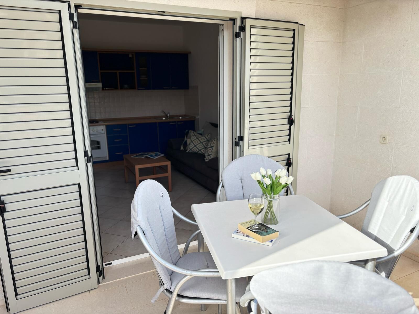 An open patio with a table, chairs, and a view into a kitchen area.
