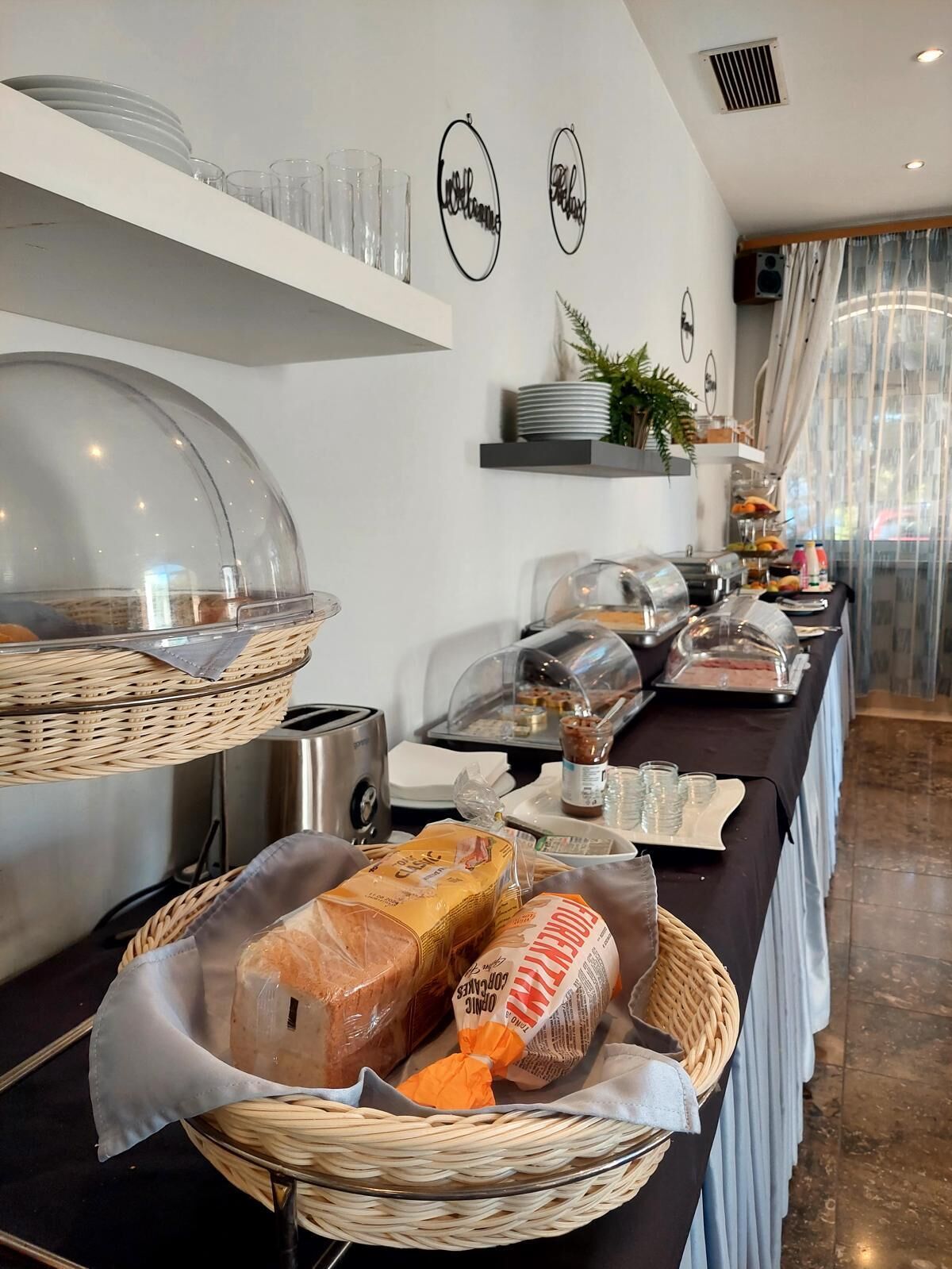 Un'impostazione per buffet con diversi cibi, tra cui pane e pasticceria, presentati in cesti e su piatti.
