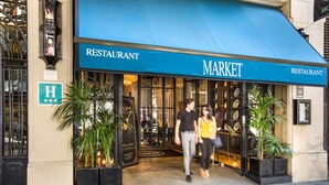 Un restaurant anomenat 'Market' amb una tenda blava i una entrada de vidre.