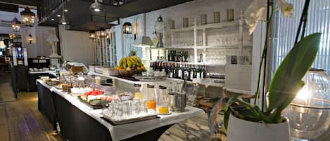 Montaje de bufé con diversos alimentos, una selección de bebidas y una estantería para vinos.