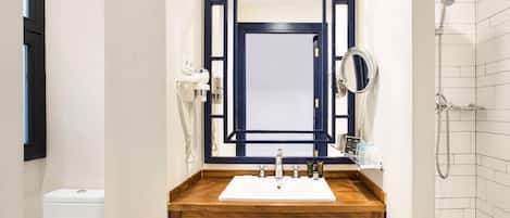 A bathroom with a wooden vanity, a mirror, a sink, and a shower.