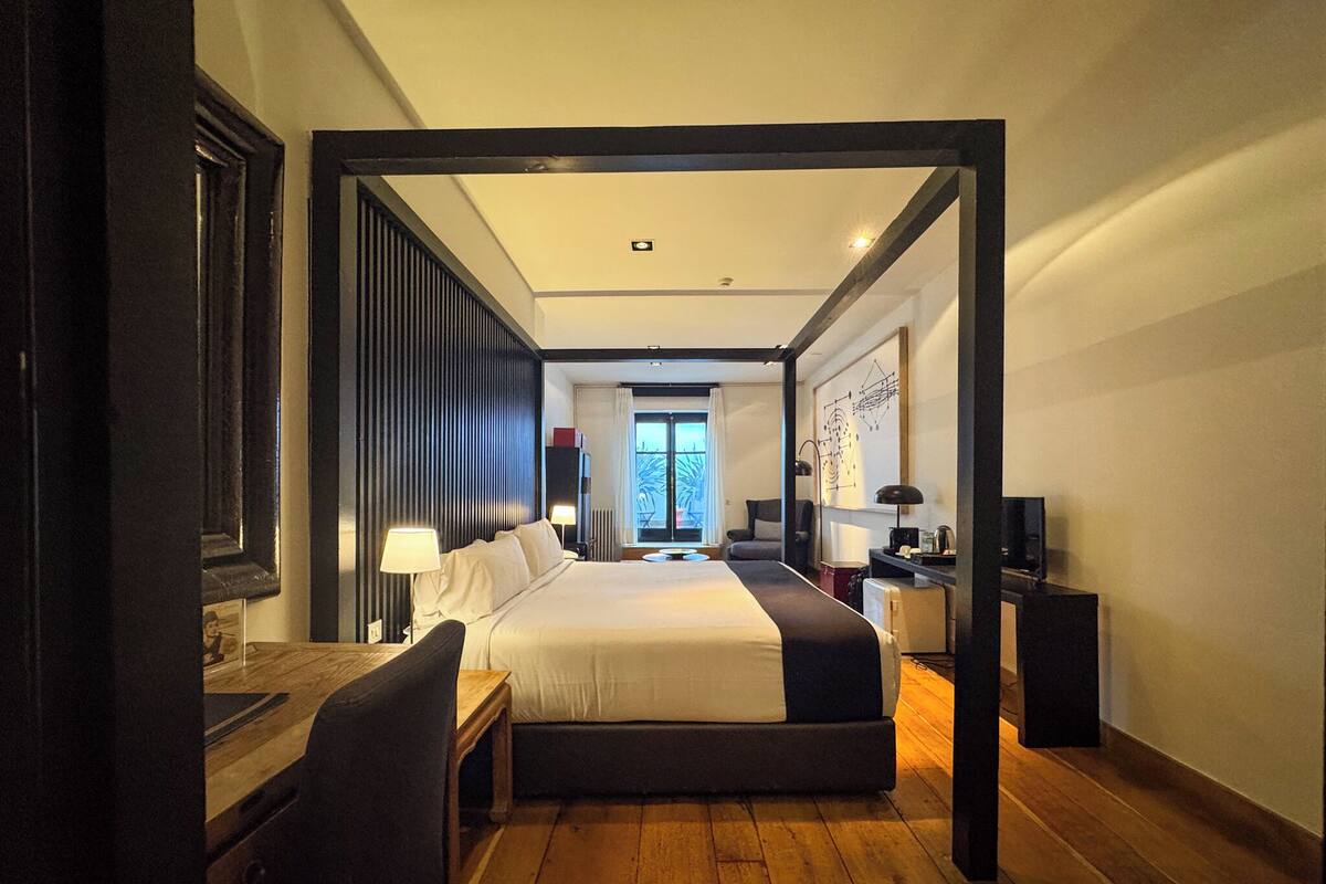 Habitación de hotel moderna con una cama grande, un escritorio y una silla. Hay una ventana con vistas al exterior.