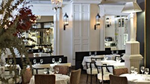 Un restaurant amb sòls de fusta, taules preparades per dinar i lluminàries penjants de llanternes.
