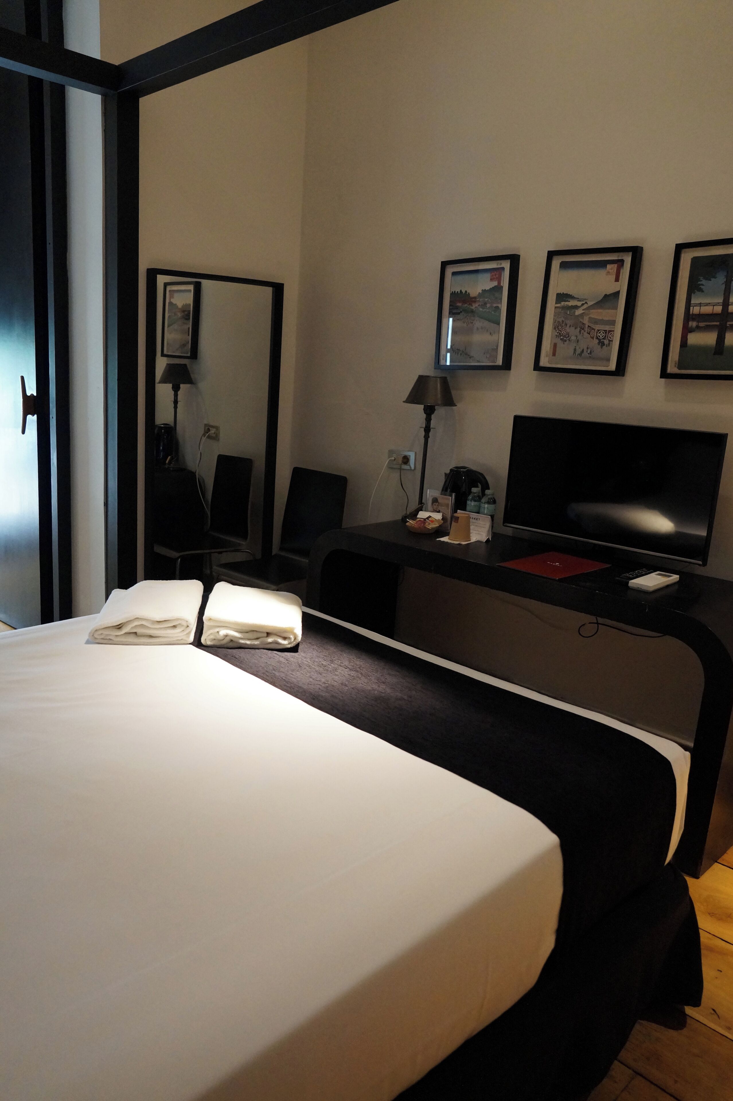 Une chambre d’hôtel comprenant un lit, un bureau avec un ordinateur, une chaise, une lampe et un téléviseur.
