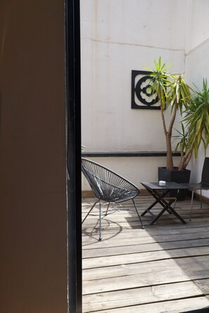 Un patio con una silla de metal, una mesa y una planta en maceta.