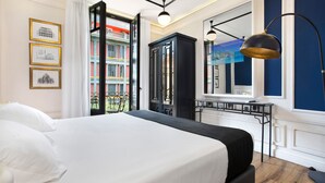 Habitació d'hotel moderna amb un llit gran, vistes a edificis de colors i un armari negre.