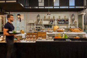 Montaje de bufé con diversas opciones de comida, una selección de vinos y una persona atendiendo.