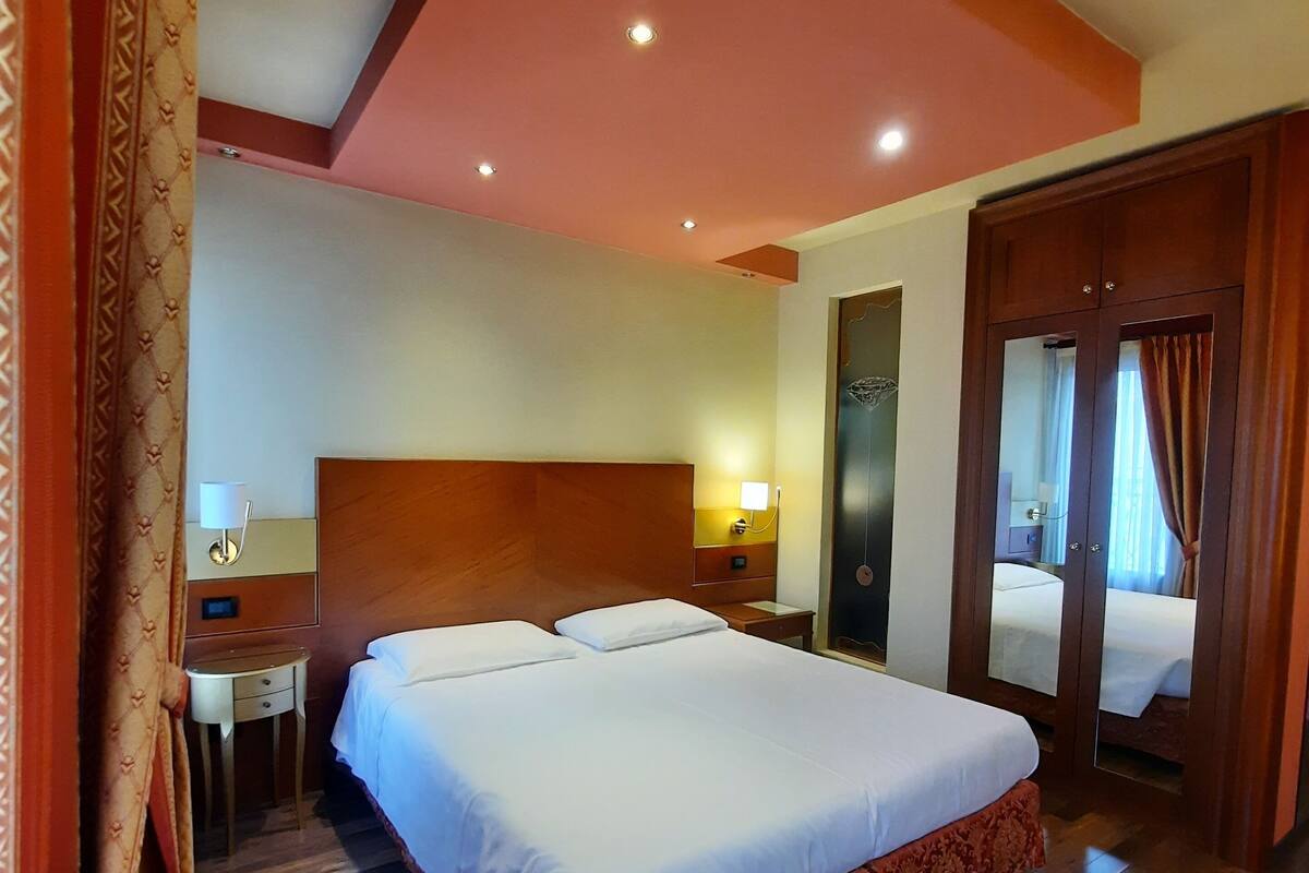 Ein Hotelzimmer mit einem großen Bett, einem Nachttisch und einem Spiegel.