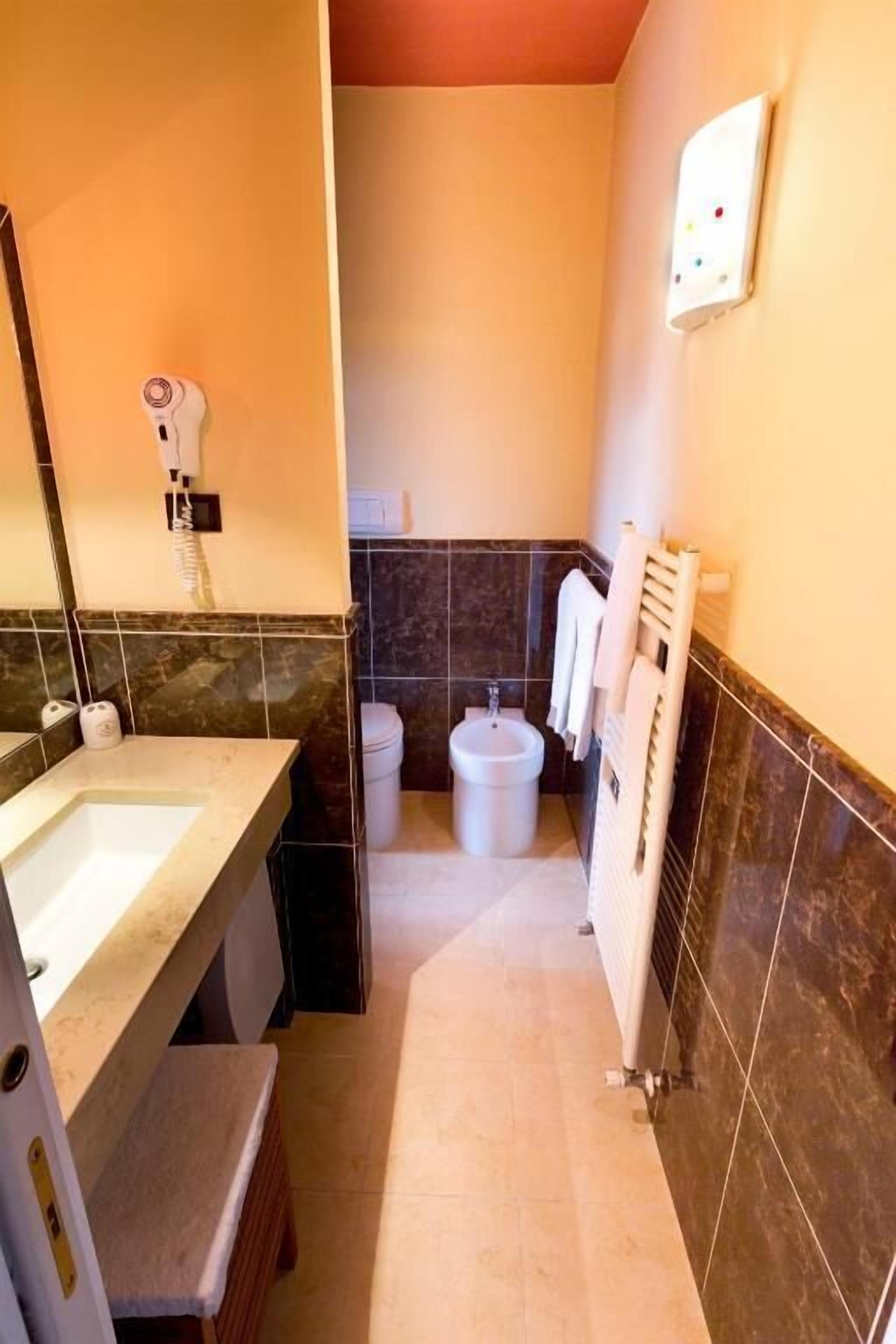 A compact bathroom with a sink, toilet, bidet, and towel rack.