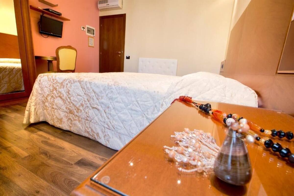 Ein Hotelzimmer mit einem Bett, einem Holztisch mit Dekoration, einem Fernseher und einer Tür.