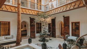 A courtyard with a pool, wooden furniture, and a palm tree. - Riad Djebel (Marrakech)