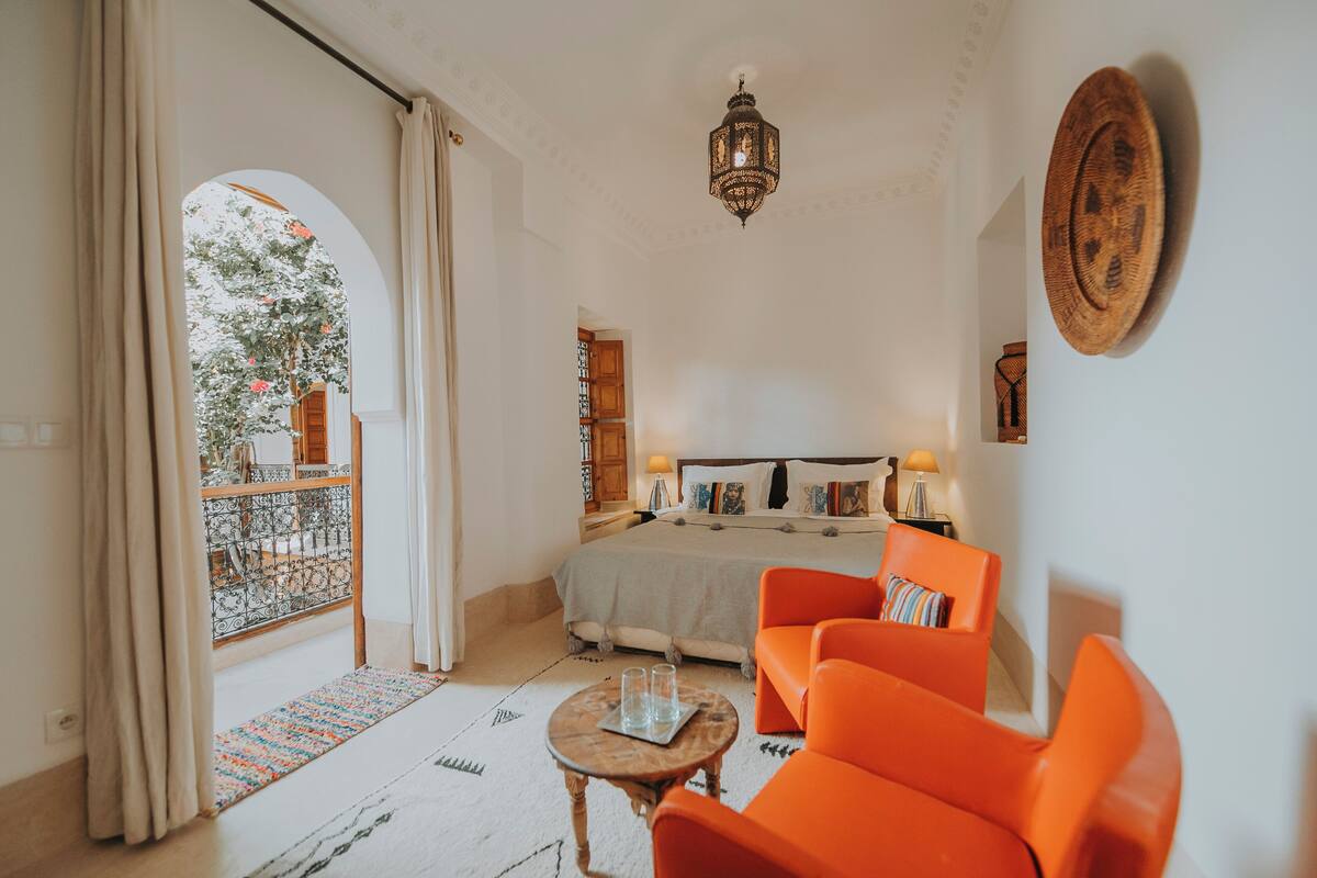 A bedroom with a bed, two bedside tables, a nightstand, and a window with curtains.