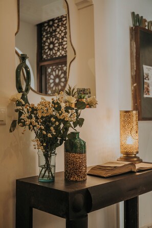 Une table avec un vase de fleurs, une bougie et un livre.