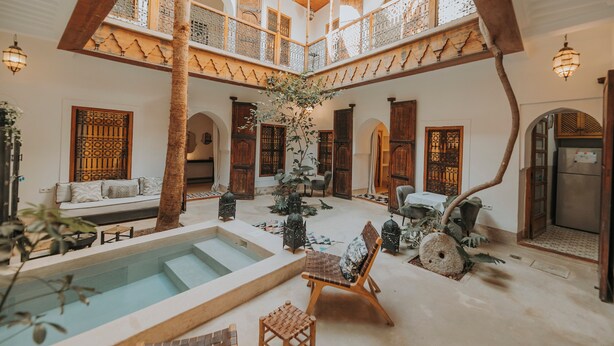 A spacious courtyard with a central pool, wooden furniture, and decorative plants. - Riad Djebel (Marrakech)
