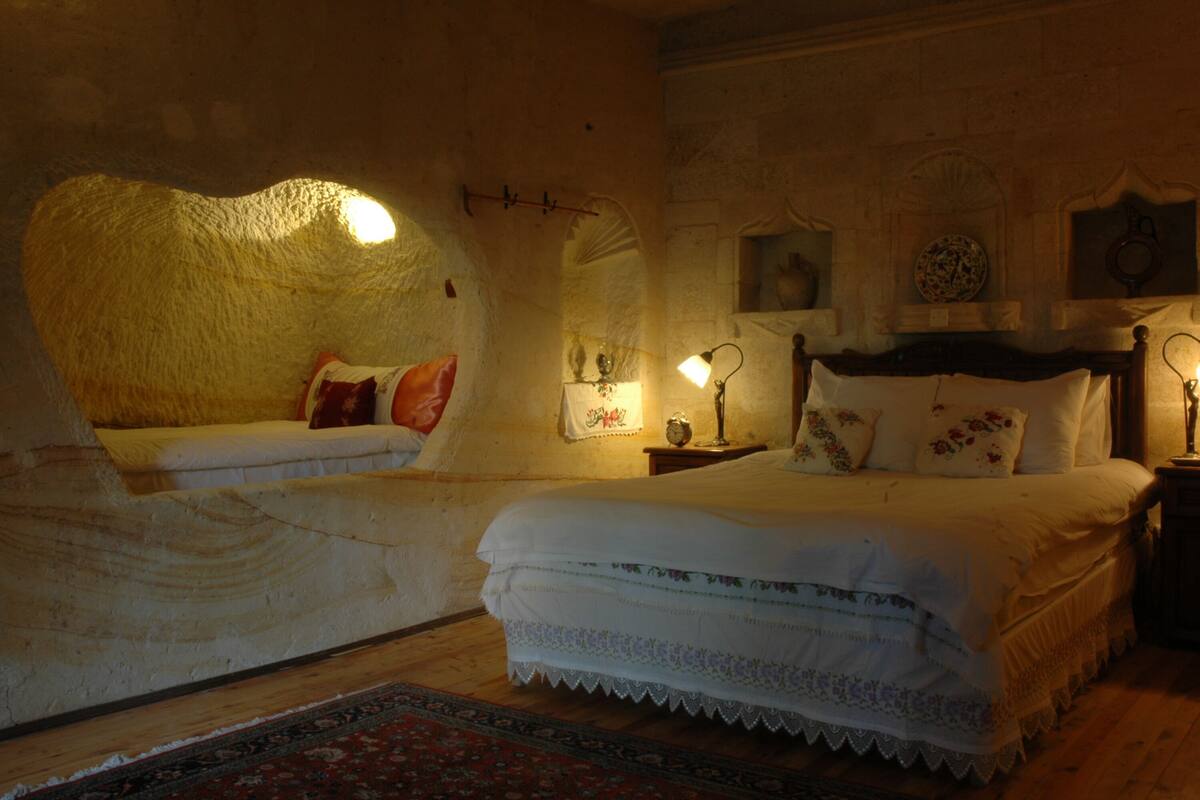 A cozy bedroom with two beds, a wooden floor, and a decorative rug.