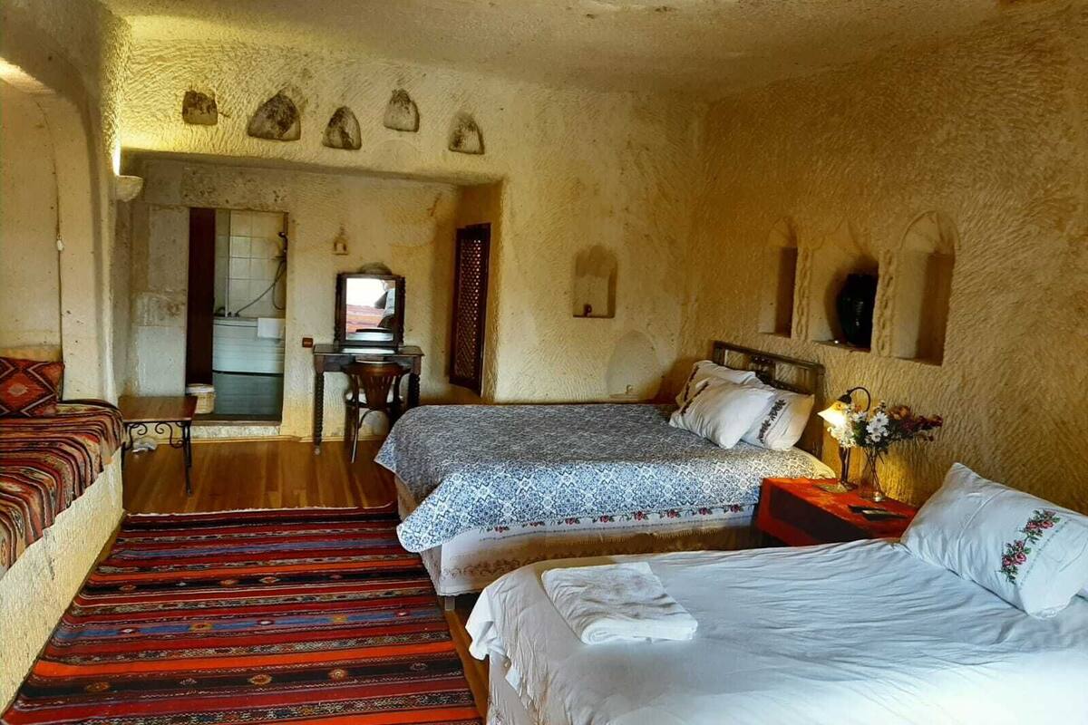 A traditional room with two beds, a sofa, a desk, and a patterned carpet.