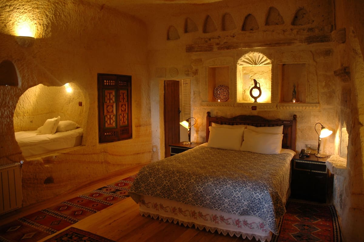 A cozy bedroom with a bed, a nightstand, a lamp, and a decorative mirror.