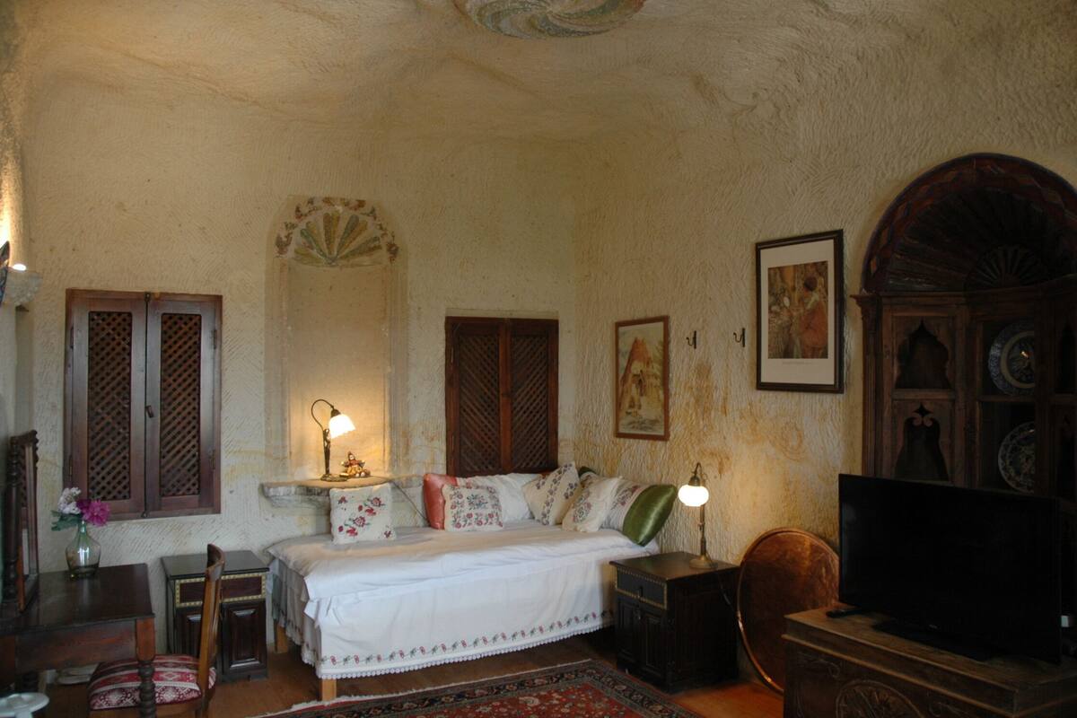 A bedroom with a bed, bedside tables, a television, and a wooden cabinet.