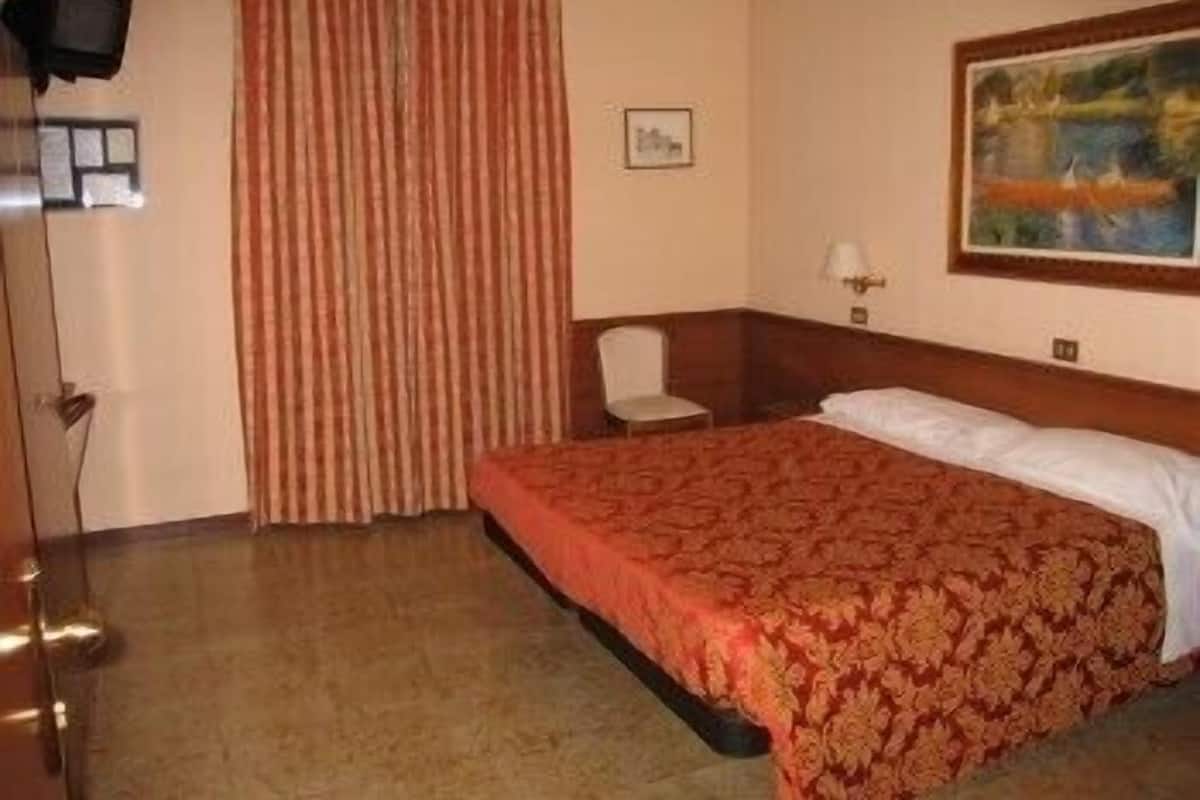 Ein Hotelzimmer mit einem großen Bett, einem Sessel, einem Fernseher und einem Bild an der Wand.