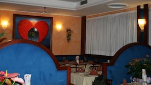 L’int érieur d’un restaurant, avec une grande œuvre d’art en forme de cœur accrochée au mur, des lambris en bois et une table dressée pour le repas.