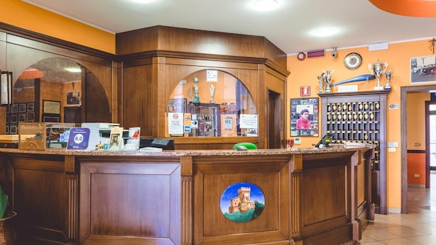 Un comptoir d’accueil au design en bois, une horloge et des photos encadrées accrochées au mur.