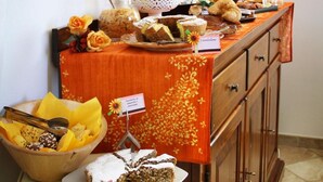 Una mesa de bufé con diversos postres y frutas, incluyendo una tarta y un bol de pastelería.