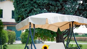 Un patio con una silla mecedora, una mesa con un florero y una sombrilla.