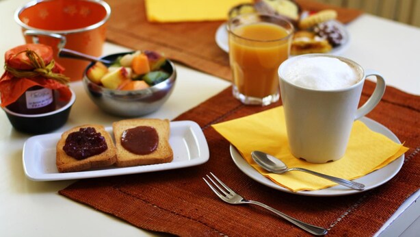 Ein Frühstückstisch mit Toast, Marmelade, Obst, Kaffee und Saft.