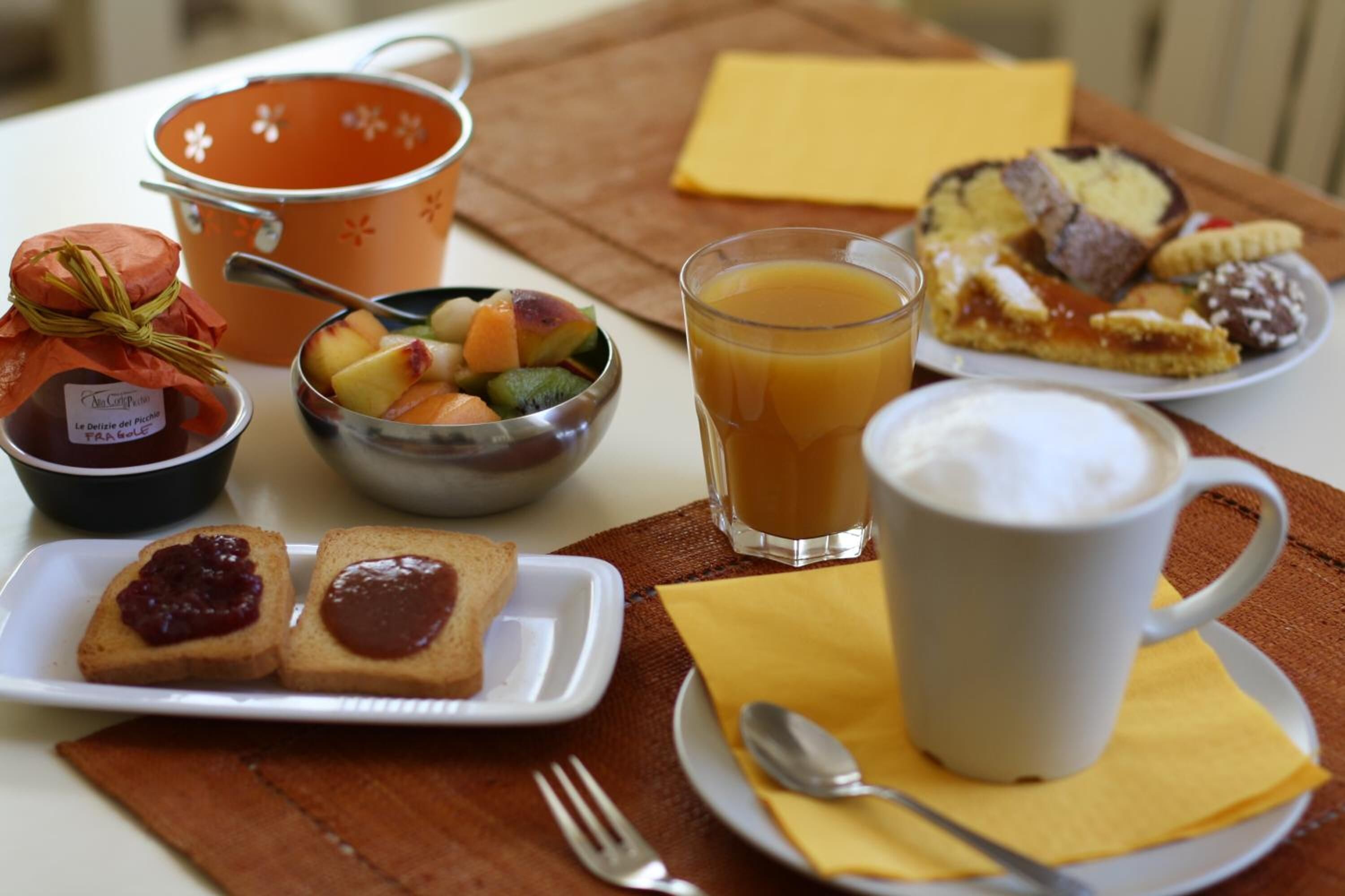 Un desayuno con tostadas, fruta, una taza de café y un muffin.
