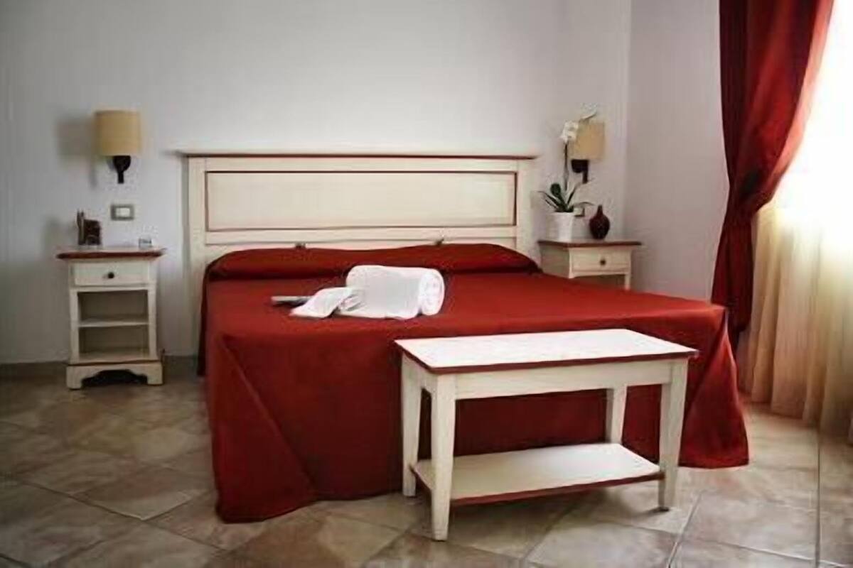 Una habitación de hotel con cama, mesita de noche y lámpara.