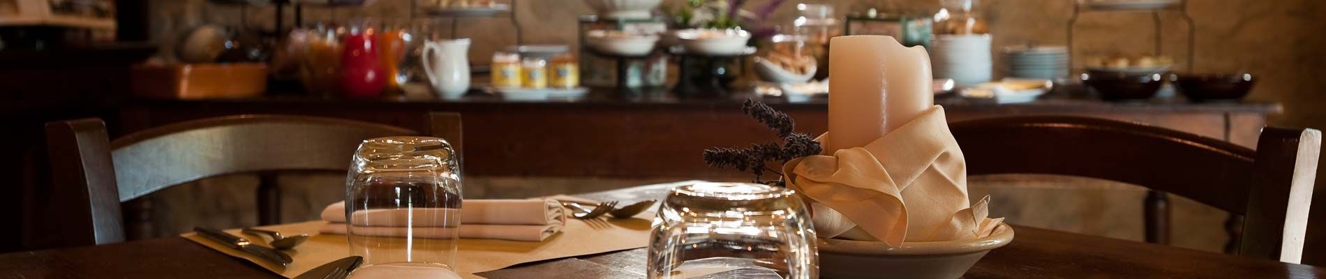 Une table à manger dressée avec une bougie, un bocal en verre et une serviette.
