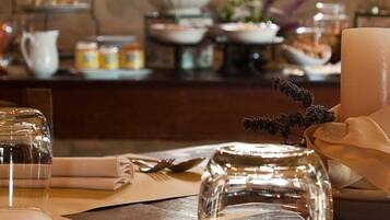 Une table à manger dressée avec une bougie, un bocal en verre et une serviette.