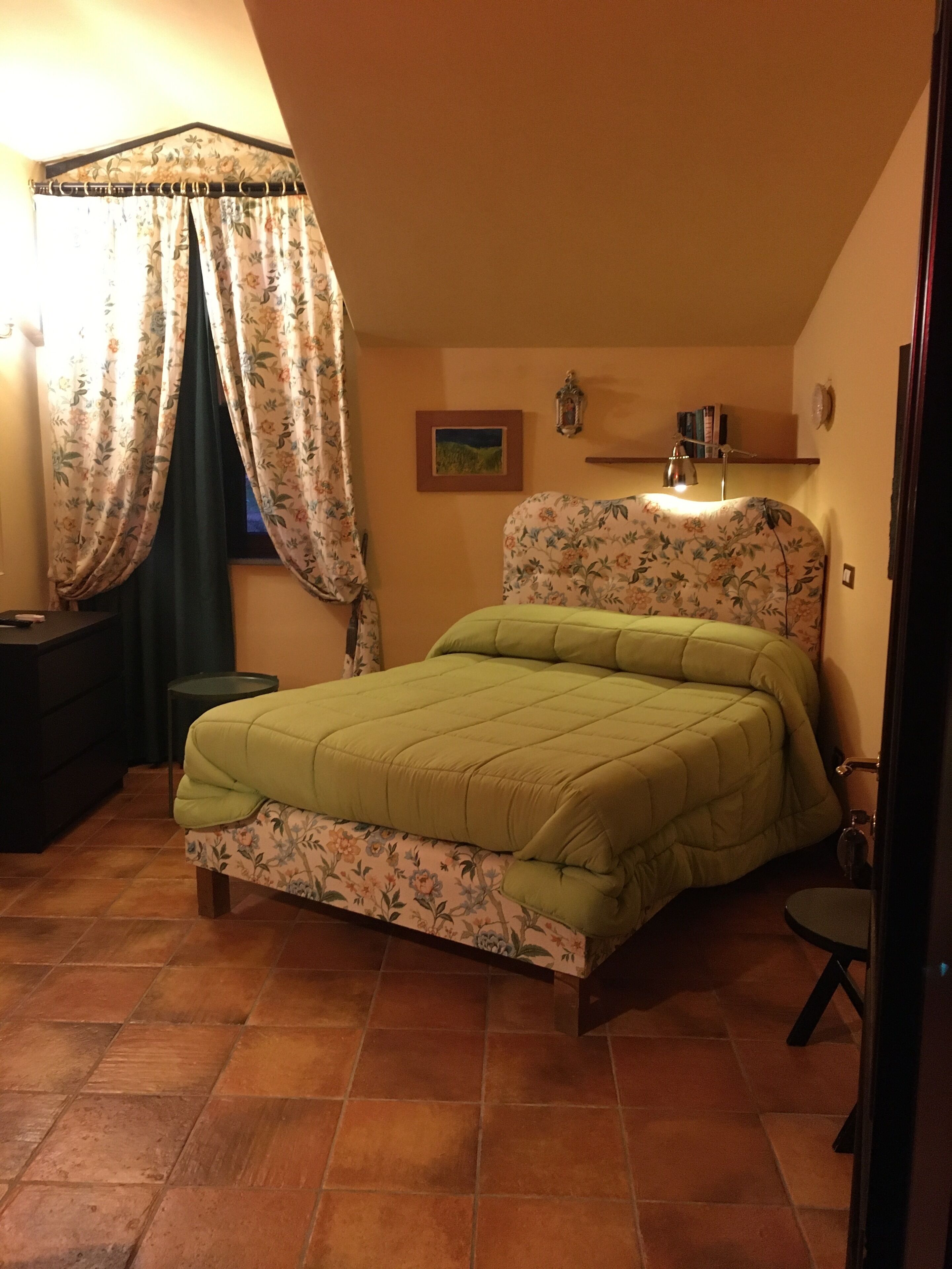 A bedroom with a bed, a desk, a chair, a lamp, and a picture on the wall.