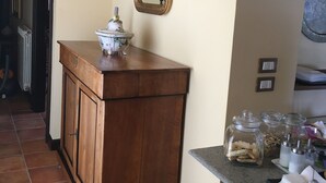A kitchen with a wooden cabinet, a wall-mounted mirror, and a countertop with jars and utensils. - MontAlbano (Caserta)