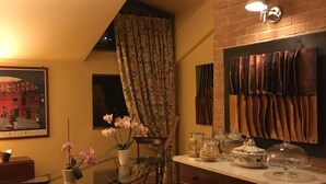 A cozy dining area with a glass table, chairs, and a vase of pink flowers. There is a brick wall and a painting on the wall. - MontAlbano (Caserta)